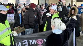 A crowd of people holding signs and one holding a megaphone at Syracuse's Federal Buidling