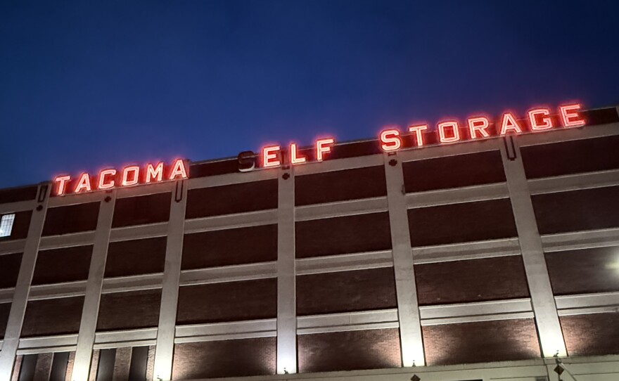 A sign in red lights on top of a building that reads "Tacoma Elf Storage."