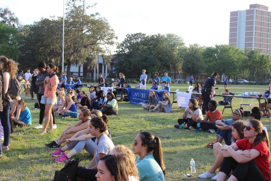 Attendees find seats on the grass during the open mic portion of the rally after rows of seats in front of the stage fill. "It takes a special kind of courage to get up there and tell everyone," Livia Ledbetter, a 19-year-old sociology sophomore said.