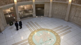 Visitors stroll through the New Mexico state Capitol building in Santa Fe, N.M., on Monday, Dec. 12, 2022. State legislators are anticipating a multibillion-dollar financial windfall largely from surging oil production and robust energy prices in the era of war between Ukraine and Russia. Lawmakers will meet in January 2023 to craft a spending plan for the coming fiscal year. One representative plans to propose lawmakers move into a more professional realm of paid legislatures. (AP Photo/Morgan Lee)