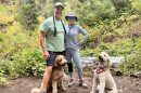 A photo of Joe and Debbi Bellinghieri hiking in Park City with their two dogs Charlee (left) and Murphee (right).
