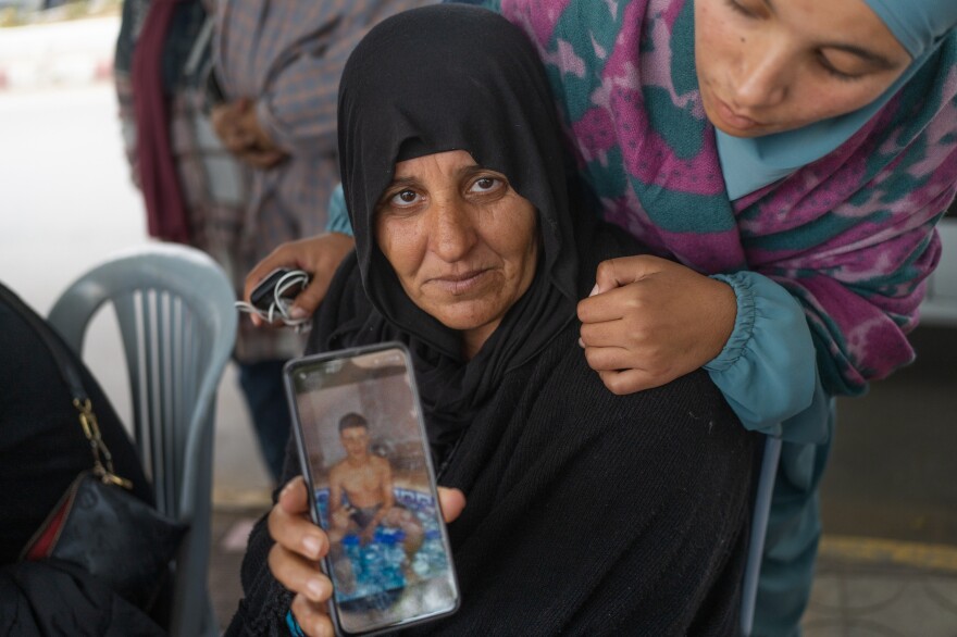 Mounira Kerimi shows a photo of her son who is still missing, as her daughter looks on.