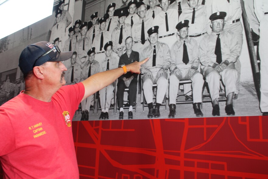 Captain Roy Harvey points out former fire department members in a historical photograph along the walls of Central Fire Station.  