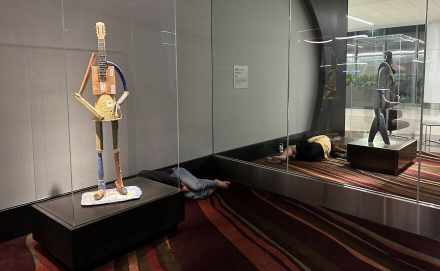 An unhoused person sleeps outside of security as a passenger sleeps inside security at SFO