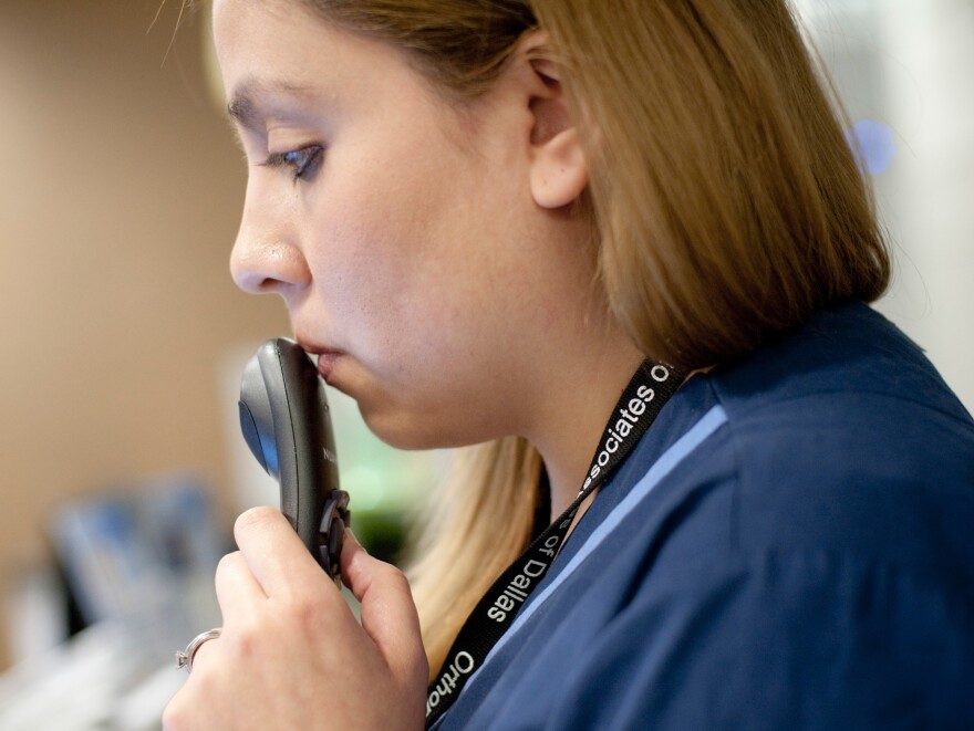 As the doctor examines a patient, medical scribe Connie Gayton records the visit using a microhone tethered to her laptop.