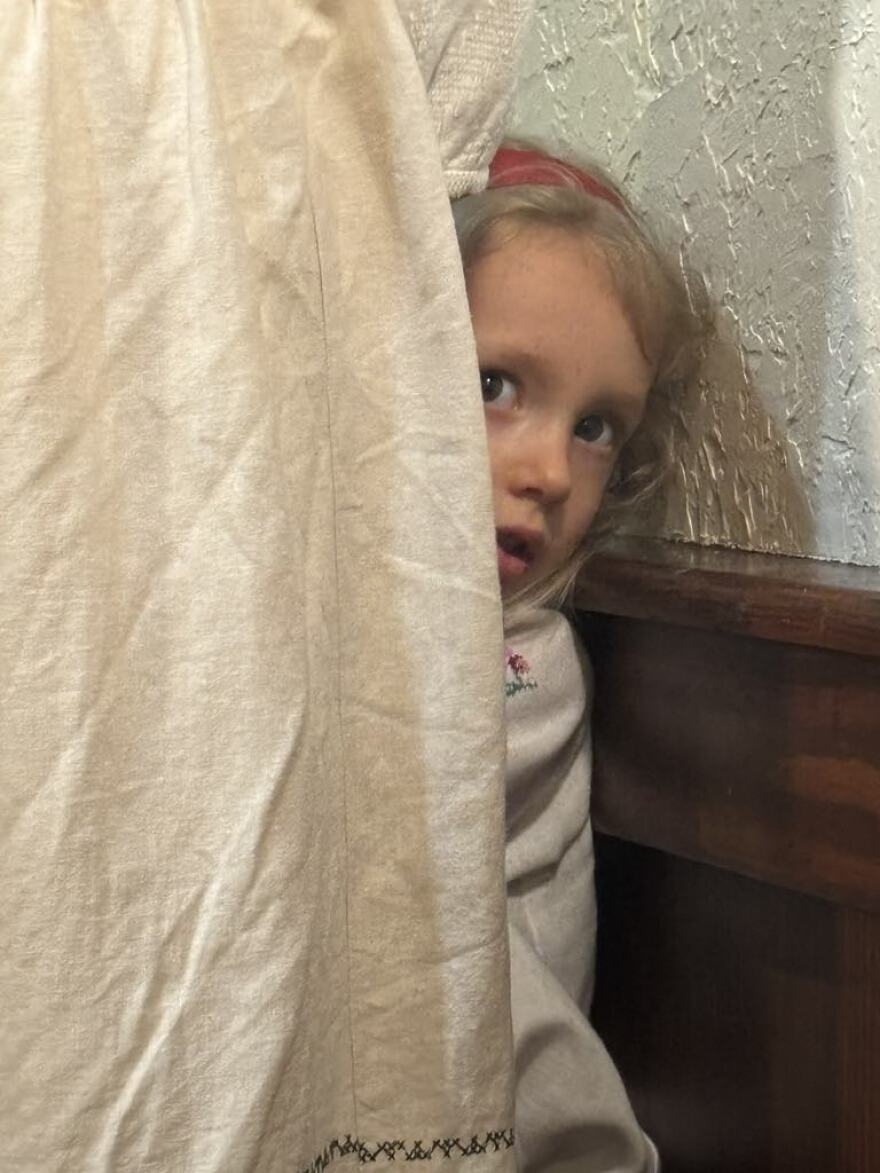 The family's youngest daughter in a shy moment hides behind her mother's skirt.