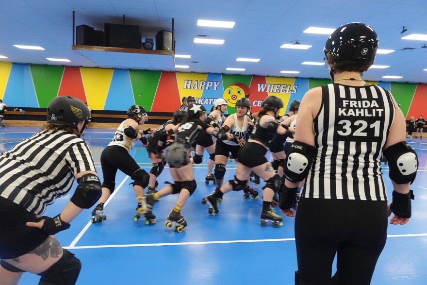 Referees watch closely as the skaters play.
