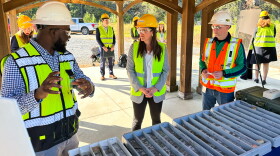 Woman and men in safety vests talk outdoors