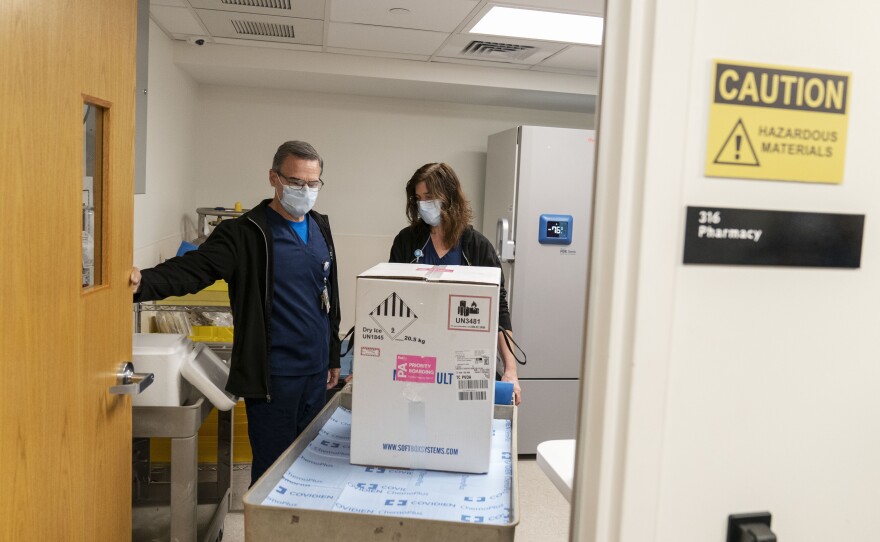 Pharmacists Richard Emery and Karen Nolan wheel a box containing the Pfizer-BioNTech COVID-19 vaccine next to a storage freezer as it arrives at Rhode Island Hospital in Providence, R.I, on Monday.
