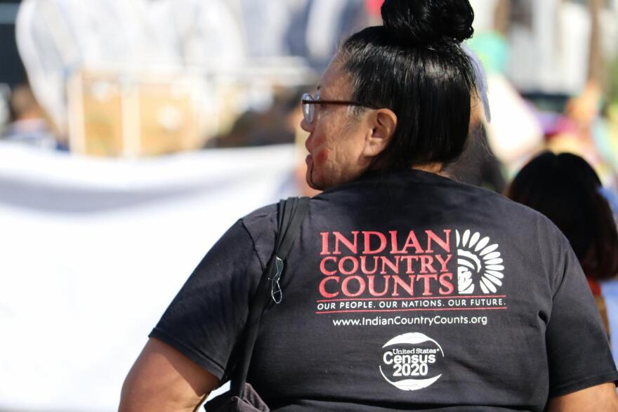 A woman walks while wearing an "Indian Country Counts" in the 39th annual Native American Connections Parade.