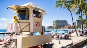 A lifeguard looks out to the beach from a lifeguard tower in Waikīkī. (February 25, 2026)