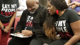Desmond Meade (left), president of the Florida Rights Restoration Coalition, fills out a voter registration form as his wife Sheena Meade looks on at the Supervisor of Elections office in Orlando, Florida. (John Raoux, File/AP)
