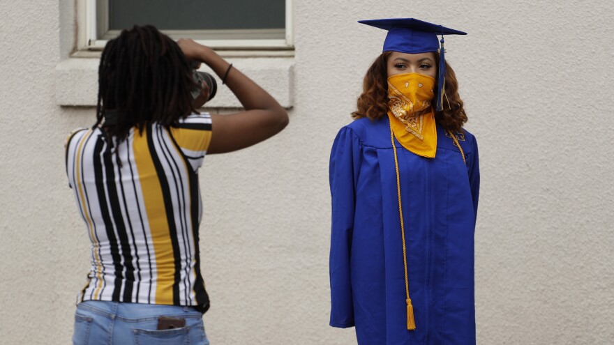 Anderson High School senior Teyaja Jones, right, poses in her cap and gown and a bandana face cover, Tuesday, May 5, 2020, in Austin, Texas.