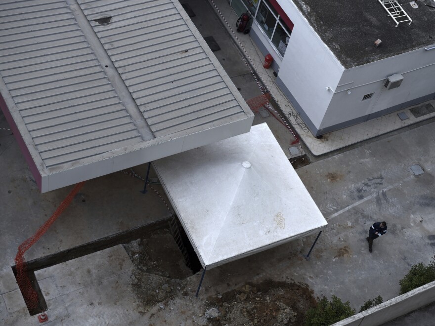 A gas station employee checks the location where an unexploded World War II-era bomb was found in Thessaloniki. This overhead shot shows just how close to the station the bomb was buried.