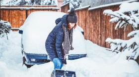 A woman shovels a deep pile of snow