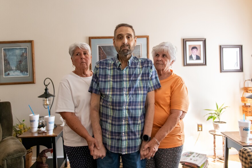 Conestoga Township, Pa: Troy Geiter stands in the living room with his mother, Dorothy Long, left, and his aunt, Carol Waltman, right. in Conestoga Township on Monday, September 9, 2024. Troy needs a second liver transplant and is one of many patients that were part of the suddenly shuttered Penn State Health transplant program. Troy said his mom and aunt have been with him through this since day one. (Susan L. Angstadt)