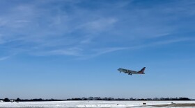 An American Airlines jet takes off from the Columbia Regional Airport runway. There is snow on the ground. 
