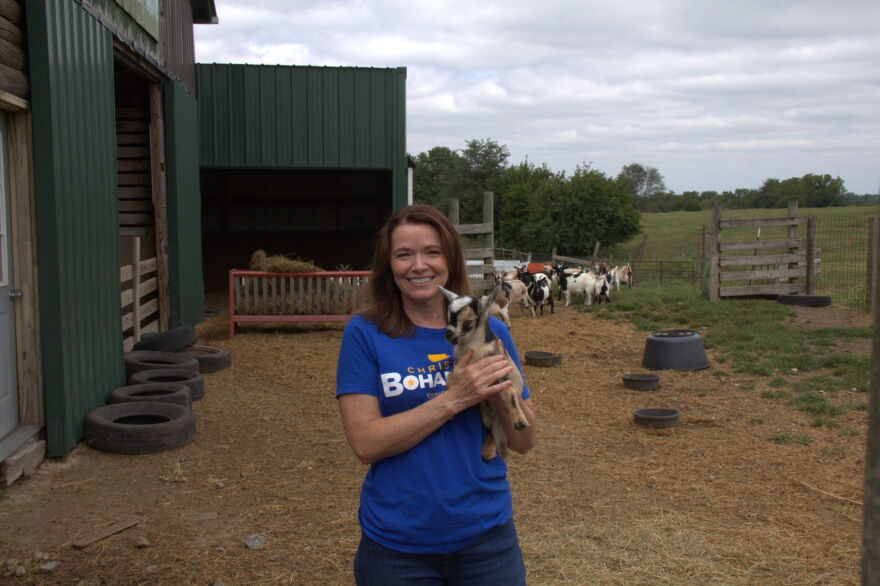 Christina Bohannan stands at a farm and holds a baby goat.