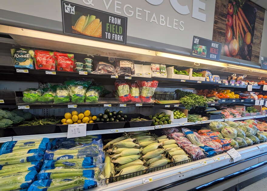 Shelves contain celery, corn, squash, green beans and other vegetables. A sign says "From Field to Fork."