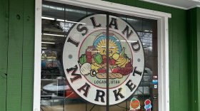 The window of a green building has a circular decal that says "Island Market"