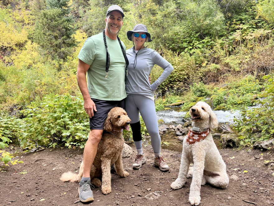 A photo of Joe and Debbi Bellinghieri hiking in Park City with their two dogs Charlee (left) and Murphee (right).