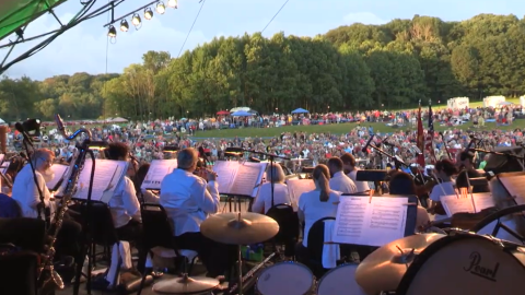 A group of musicians play on a stage as an audience watches.