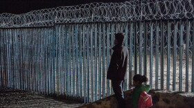 A young man and a little girl look at the border fence from Playas de Tijuana, Mexico. Photojournalist Ariana Drehsler has been covering the caravan of migrants for weeks. In December, Customs and Border Protection agents began pulling her over for questioning each time she crossed back into the U.S.