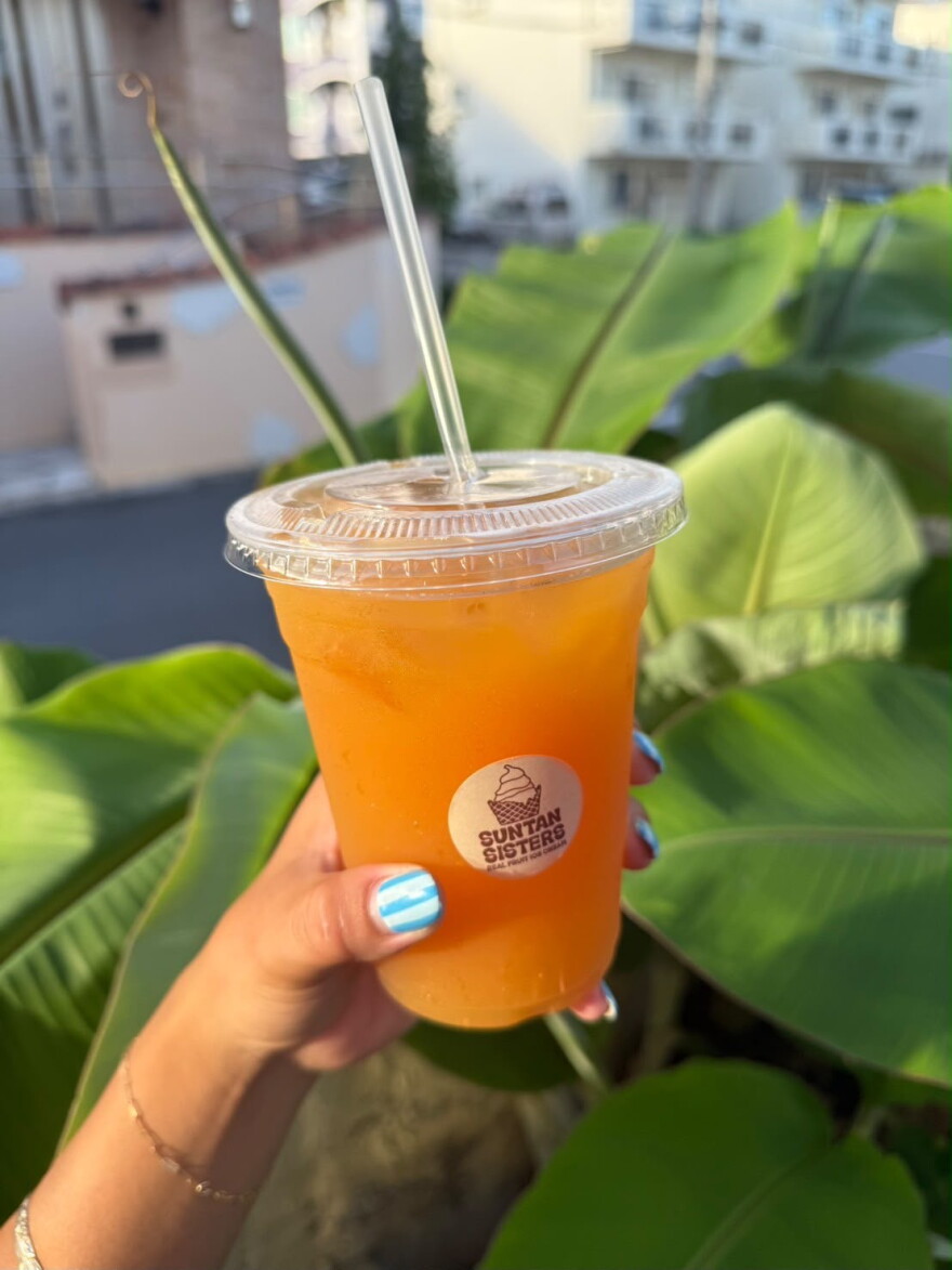 Hand holding orange looking juice