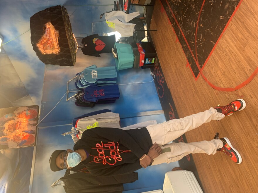  Karl Lewis tends over a pop-up sneaker shop that includes artist Aaron Fowler's renderings of characters Lewis plans to include in a comic book about sneaker culture. 