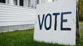 The 2020 general election is November 3. A sign that says "vote" in capital letters sits in a yard. 