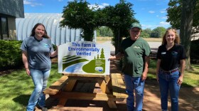 An Ottawa County farm holding a sign that shows they have been certified by Michigan Association of Conservation Districts through the MAEAP program.