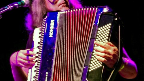 A man sitting playing an accordion. 