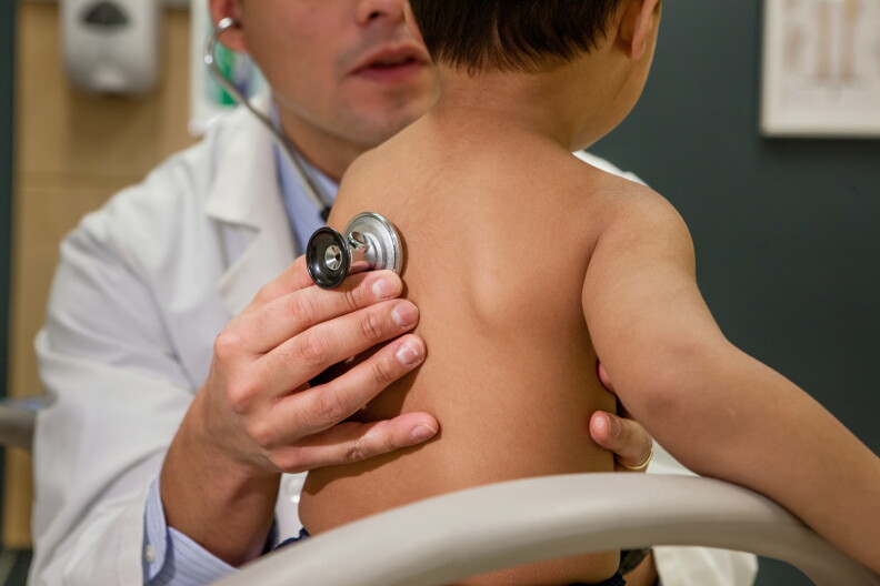 A doctor listens to a child's breathing.
