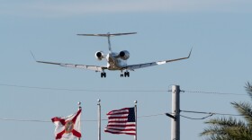 A private jets flies over US and Florida flags