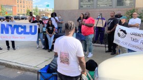 Ryedell Davis speaks to the crowd gathered between Syracuse City Hall and the state office building. The I-81/I-690 interchange can be seen in the distance.