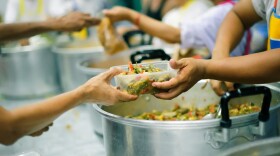 Large pots of mixed food, and hands passing a container with food in it to others' hands