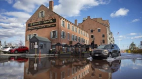 A car drives through flood water by the Chart House on Boston's Long Wharf during a November king tide.