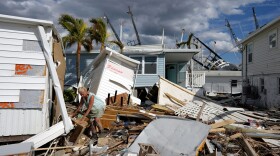 A homeowner picks through debris from destroyed trailers in the mobile home park where she had a winter home on San Carlos Island in Fort Myers Beach, Fla., Oct. 5, 2022, one week after the passage of Hurricane Ian. (Rebecca Blackwell/AP)