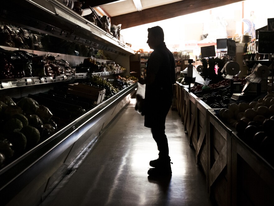 A customer shops for groceries at La Tapatia Market during a blackout in Napa, Calif., as the state's utility giant PG&E carries out a wide-scale intentional blackout to keep power lines from sparking blazes.