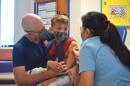 A Children's Mercy Hospital nurse uses a "shot blocker" to reduce seven-year-old Silas Mesimer's anxiety before he gets his vaccine.