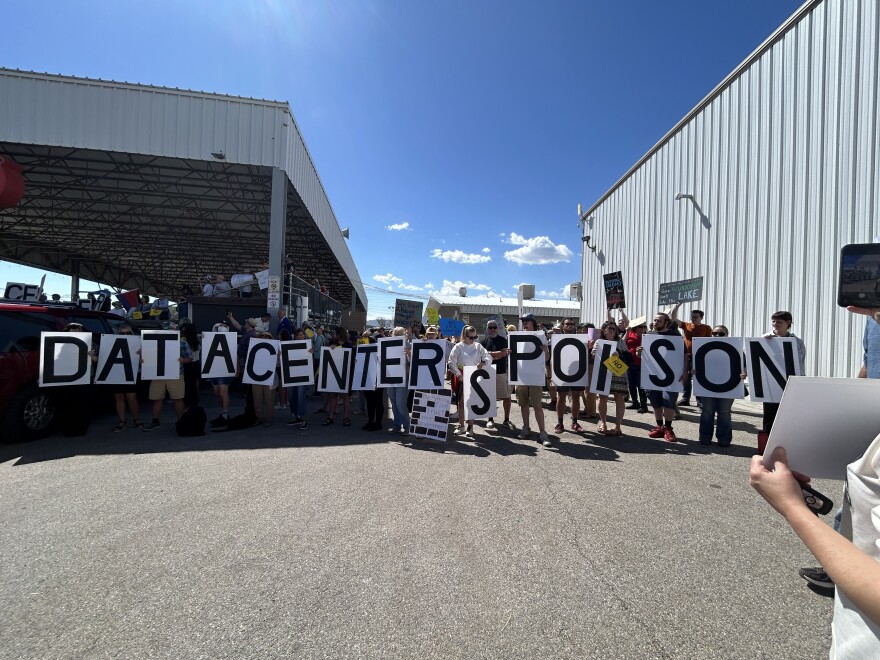A group of people hold up various letter signs, spelling out "Data centers poison"