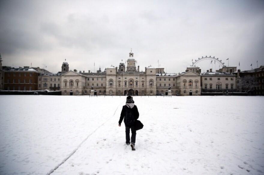 A man walks across a snowy Horse Guards Parade in London, England.