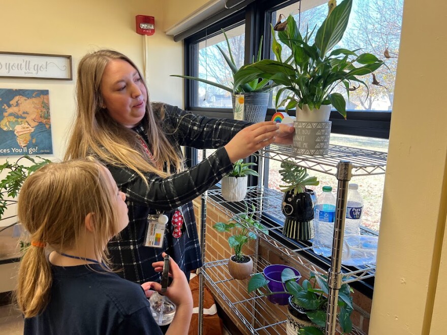 Shauna Barnes, a school counselor at Woodman Elementary School in Wichita, helps third-grader Reagan check and water plants in the staff lounge. Woodman recently launched a program called Meaningful Work, which pairs children with adult mentors to do jobs around the school.