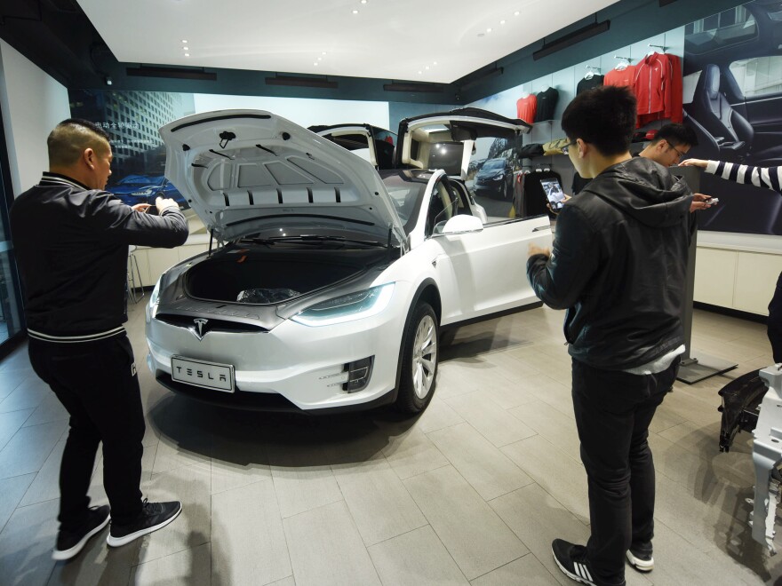 Customers look at Tesla cars at a showroom in Hangzhou in China's eastern Zhejiang province on April 4, 2018.