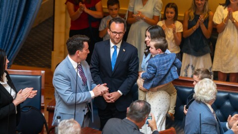 Justice Stephen Dent stands after the Utah Senate votes to confirm him, 25 to 4, to join the Utah Supreme Court, June 17, 2026. He stands by his wife and family as lawmakers applaud him.