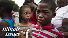 A boy holds a candle at a memorial for his 19-year-old cousin who was shot to death in Chicago.