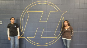 Haslett High School students Aikem Gill (left) and Nanaty Assefa (right) stand next to Haslett High School logo painted on a school wall