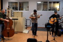 musical trio playing upright bass fiddle, mandolin and acoustic guitar in a radio studio performing 