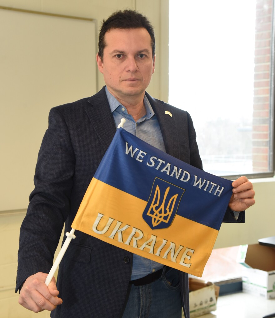  Dmitry Burshteyn, associate professor of psychology at Siena College, holds an "We Stand with Ukraine" flag. 