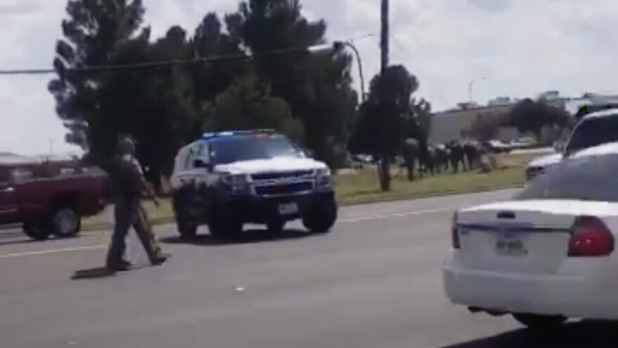 In this image made from video provided by Dustin Fawcett, police officers guard a street in Odessa, Texas. A suspect killed and injured multiple people in a mass shooting on Saturday.